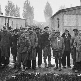 Group Portrait of Survivors Standing Next to the Moat in the Dachau Concentration Camp Following Liberation