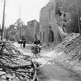 French Civilians Travel by Bike through a Destroyed French Village