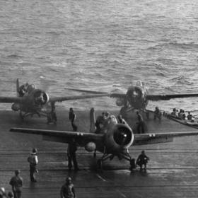 USS Kitkun Bay Prepares to Launch Planes as USS White Plains Takes Japanese Fire in Background