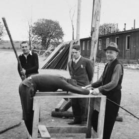 Ohrdruf Concentration Camp Survivors Reenact Torture Scenes while an American Soldier Looks On