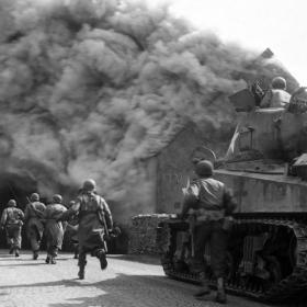 Soldiers of the 11th Armored Division Run Through a Smoke-Filled Street in Wernberg, Germany