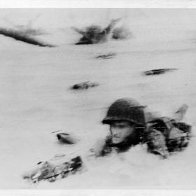 This doughboy shows how to go through breast high water under heavy artillery and machine gun fire on the French coast.